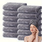 Stack of gray towels with a woman using one of them on her head.
