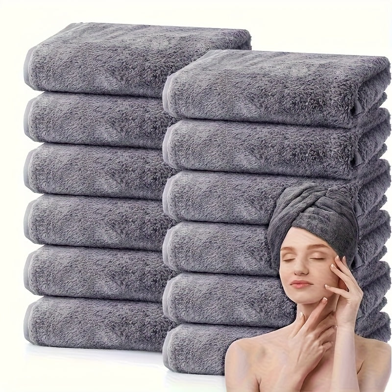 Stack of gray towels with a woman using one of them on her head.