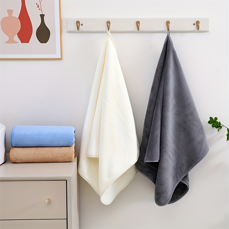 White, beige, and blue towels hanging on a wall with a cabinet below.