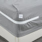 Gray striped mattress cover with a visible brand label on a bed.
