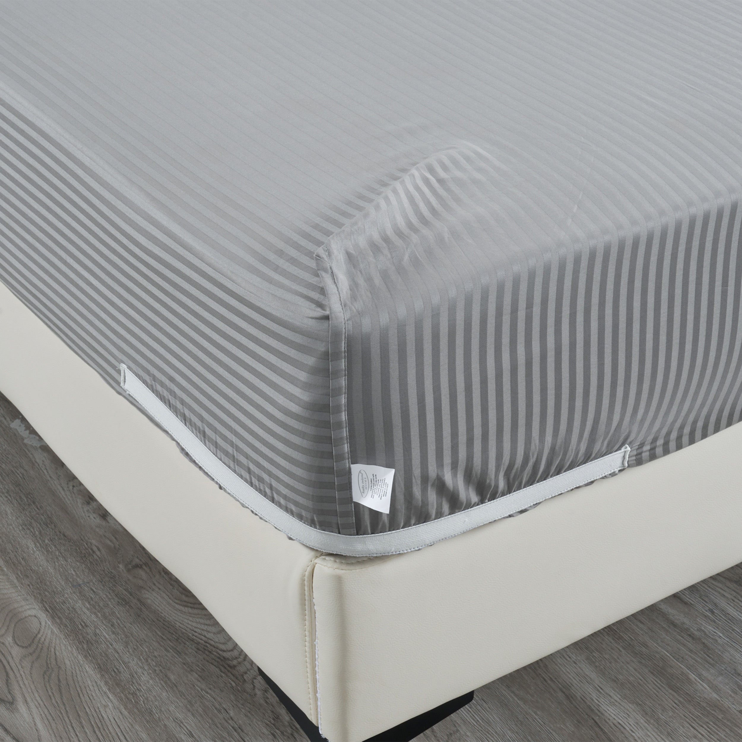 Gray striped mattress cover on a bed with a wooden floor.