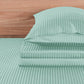 Teal striped bed sheets and pillowcase set on a wooden bed frame.