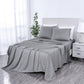 Gray striped bedspread on a bed in a bedroom setting with white walls and a nightstand.