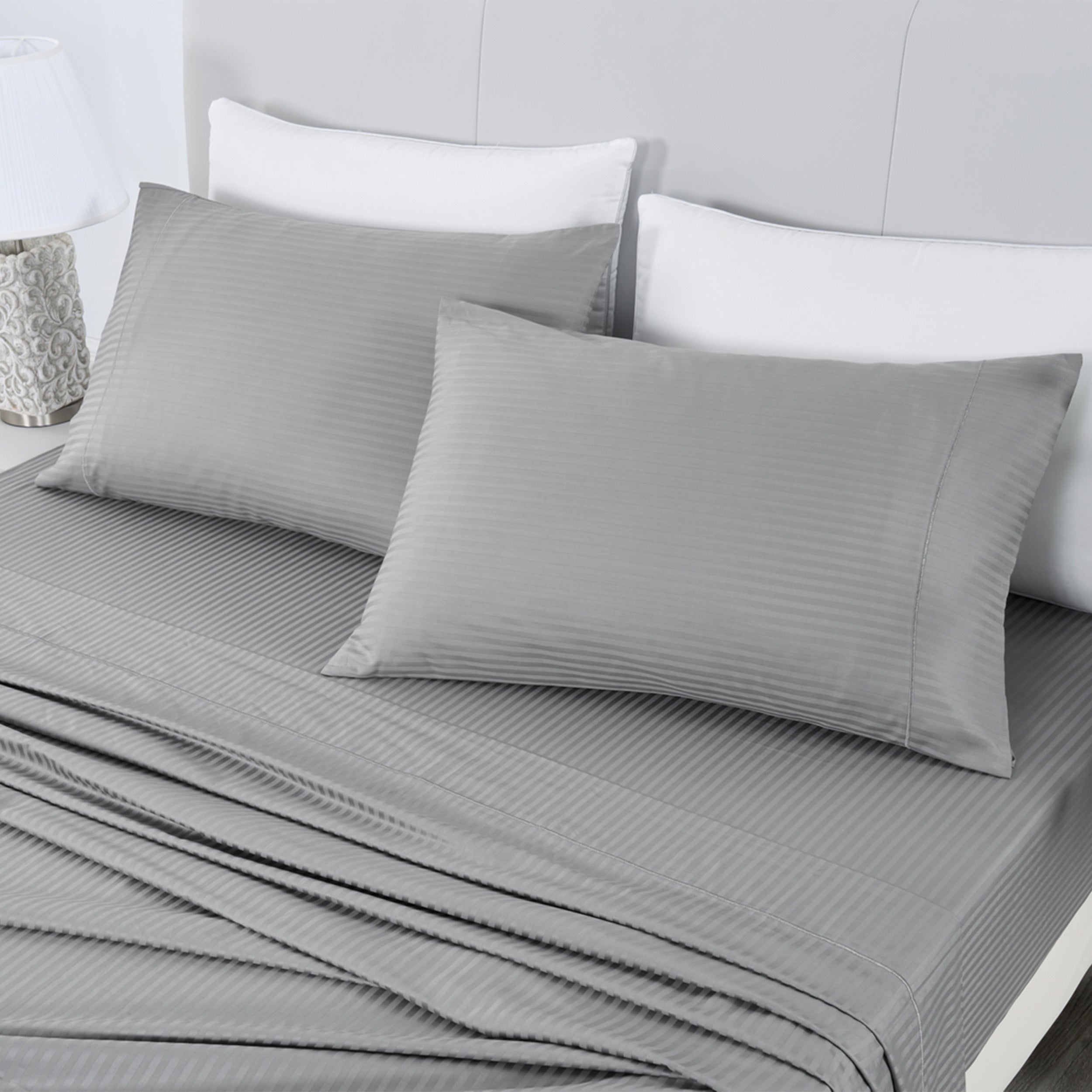 Gray striped bedding set on a bed with white pillows.