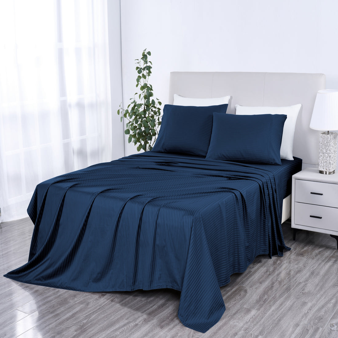 Blue bedspread on a bed in a bedroom setting with white pillows and a nightstand.