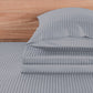 Gray striped bed sheets and pillowcase set on a wooden bed frame.