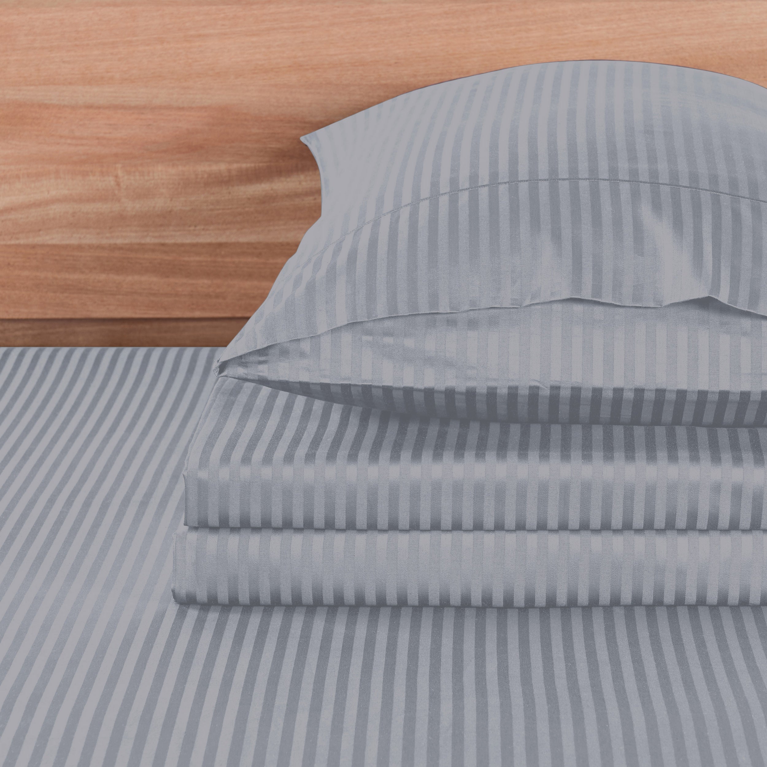 Gray striped bed sheets and pillowcase set on a wooden bed frame.