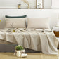 Neatly made bed with beige bedding in a bedroom setting.