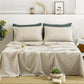 Neatly made bed with beige bedding and green pillows in a bedroom setting.