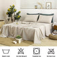 Neatly made bed with beige bedding and gray pillows in a bedroom setting.