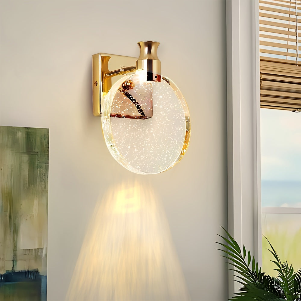 Gold wall sconce with a round glass shade on a neutral wall.