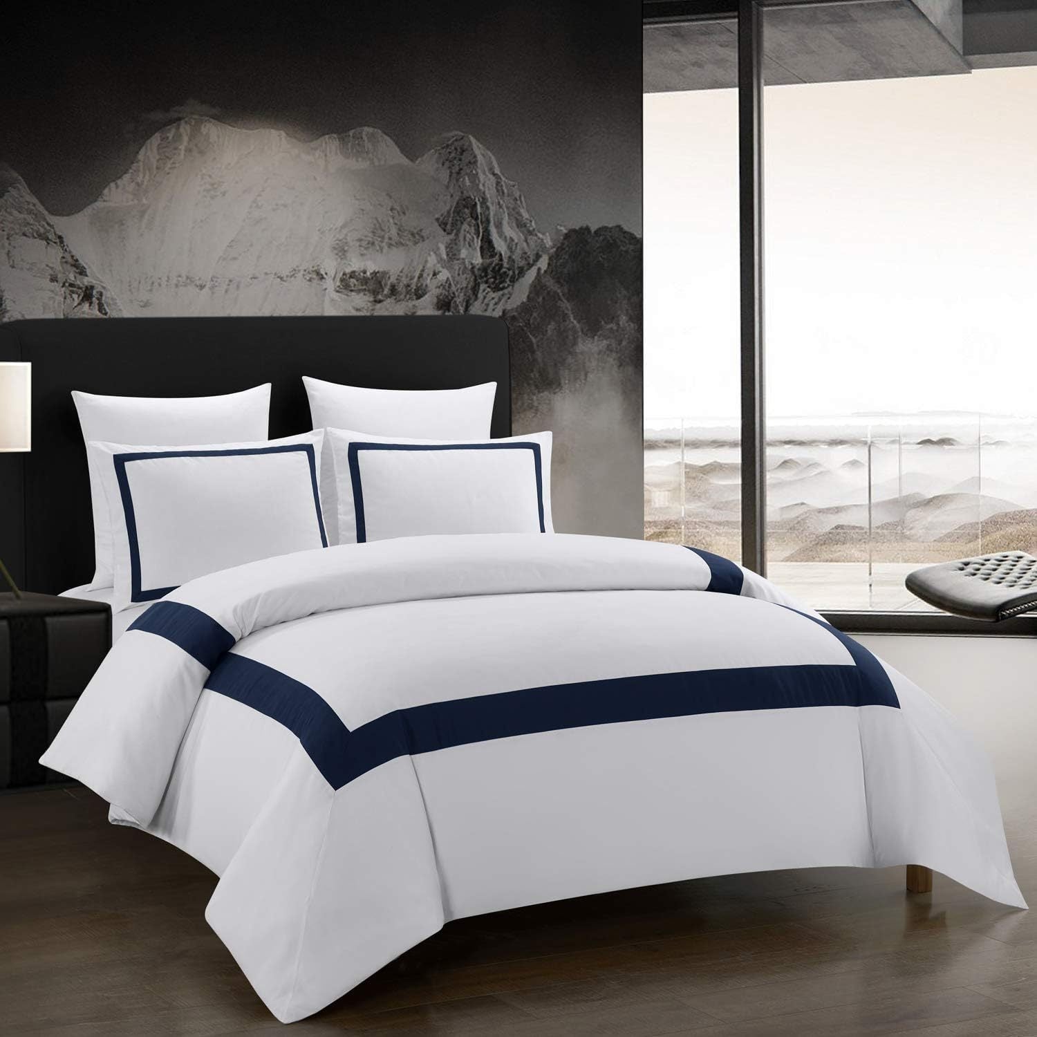 White bedding set with navy trim on a bed in a modern bedroom.