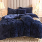 Navy blue fuzzy comforter set on a bed with pillows in a bedroom setting.
