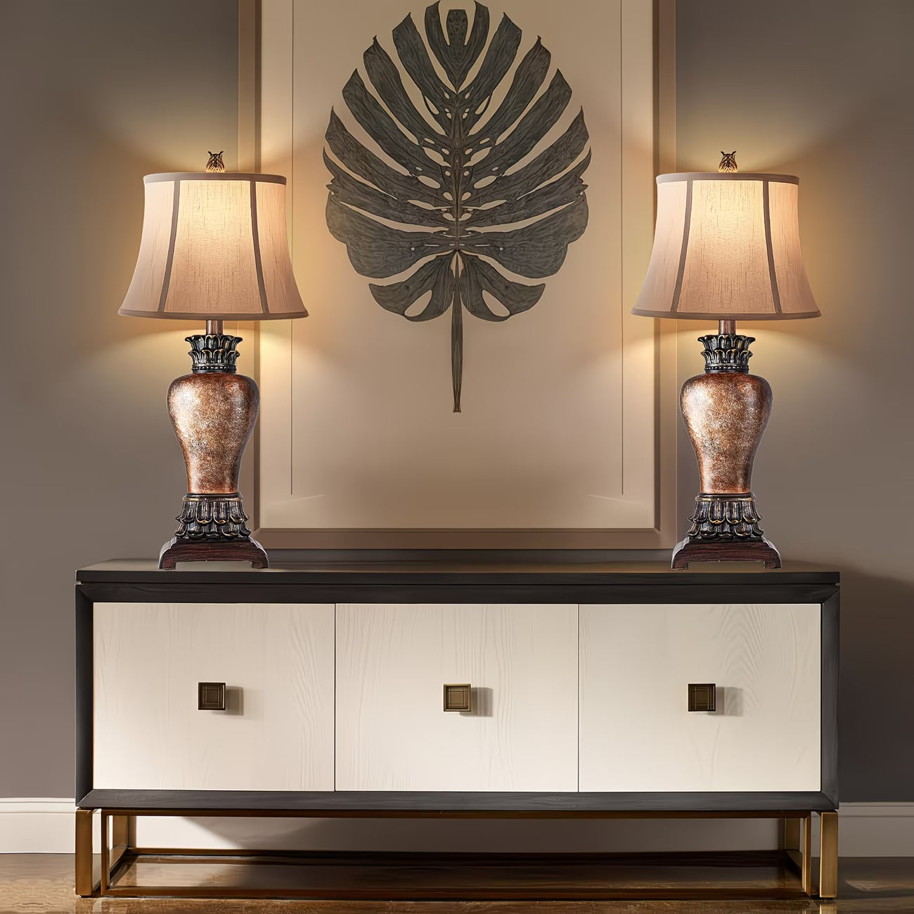 Two table lamps on a console table with a decorative wall piece in the background.