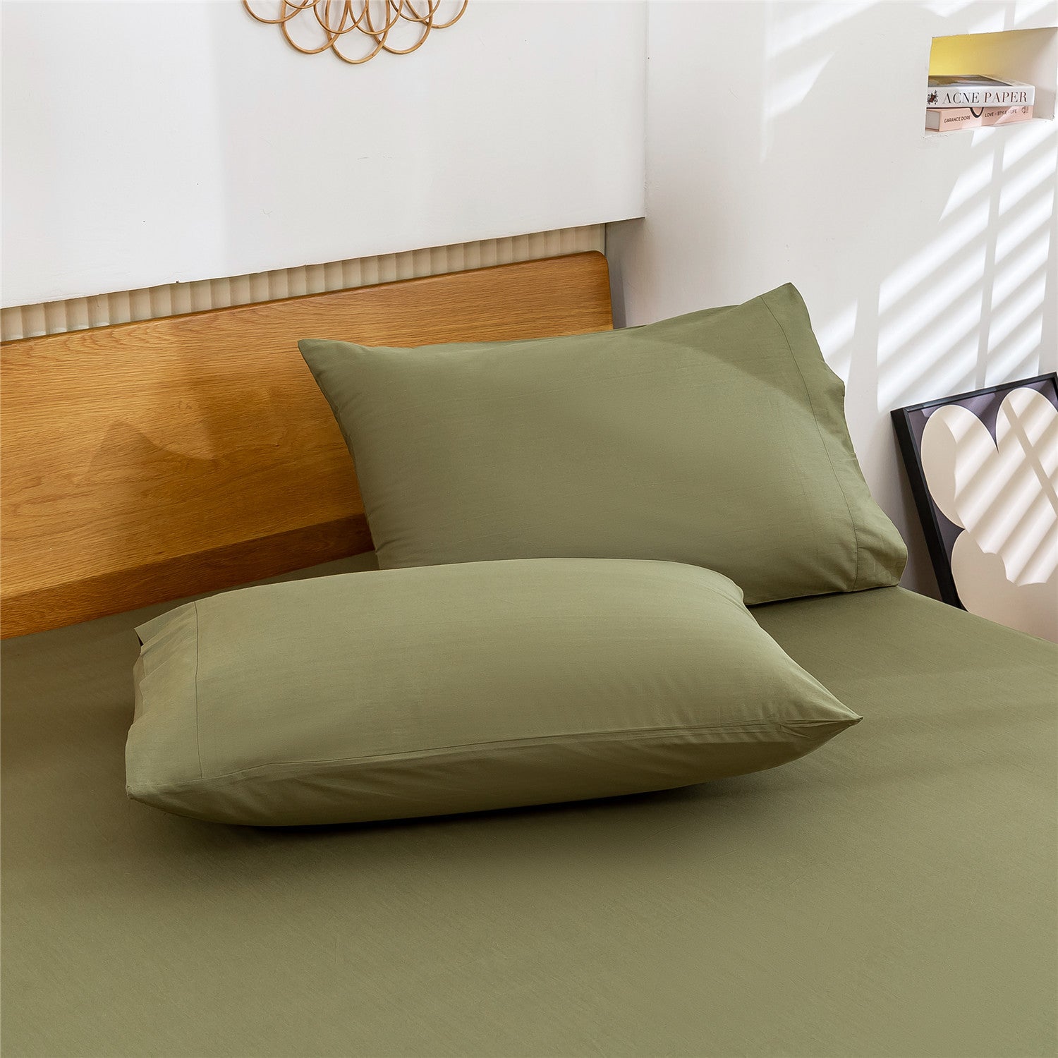 Green bed sheets and pillows on a bed with a wooden headboard.