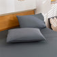 Gray bedding set with two pillows on a bed in a bedroom setting.