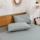 Gray bedding set on a bed with a wooden headboard in a bedroom setting.