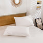 White pillows on a bed with a wooden headboard and decorative mirror.