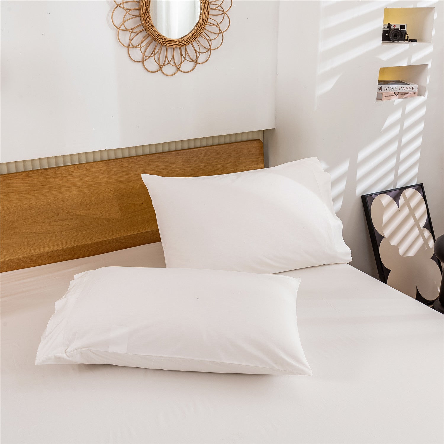 White pillows on a bed with a wooden headboard and decorative mirror.