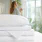 Stack of white bed sheets with a blurred background of a woman sitting by a window.