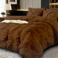 Brown textured comforter on a bed in a bedroom setting with decorative pillows and a lamp.