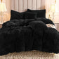 Black fluffy comforter on a bed with pillows in a bedroom setting.
