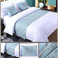 Bed with white bedding and light blue decorative runner in a bedroom setting