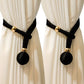 Black curtain tiebacks with gold accents on white curtains
