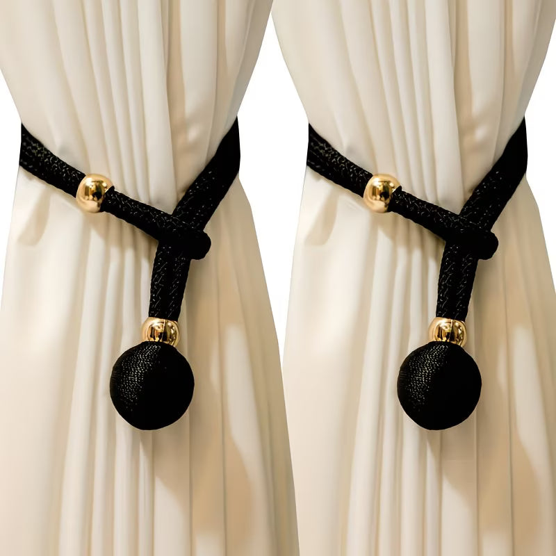Black curtain tiebacks with gold accents on white curtains