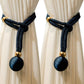 Curtain tiebacks with black balls and gold accents on beige curtains