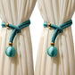 Teal curtain tiebacks with gold accents on white curtains