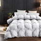 White quilted comforter on a bed in a dark themed bedroom