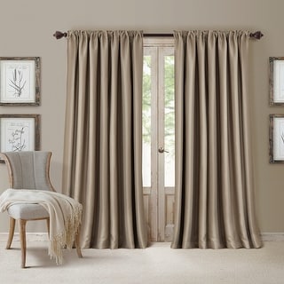 Beige curtains hanging in front of a window with a chair and decorative elements in the room.