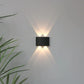 Modern wall-mounted light fixture on a plain wall with a plant in the corner.