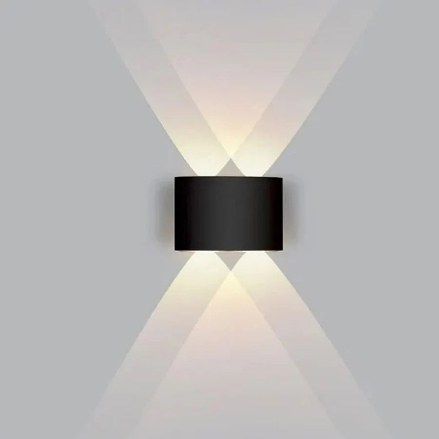 Black wall-mounted light fixture casting light on a gray wall