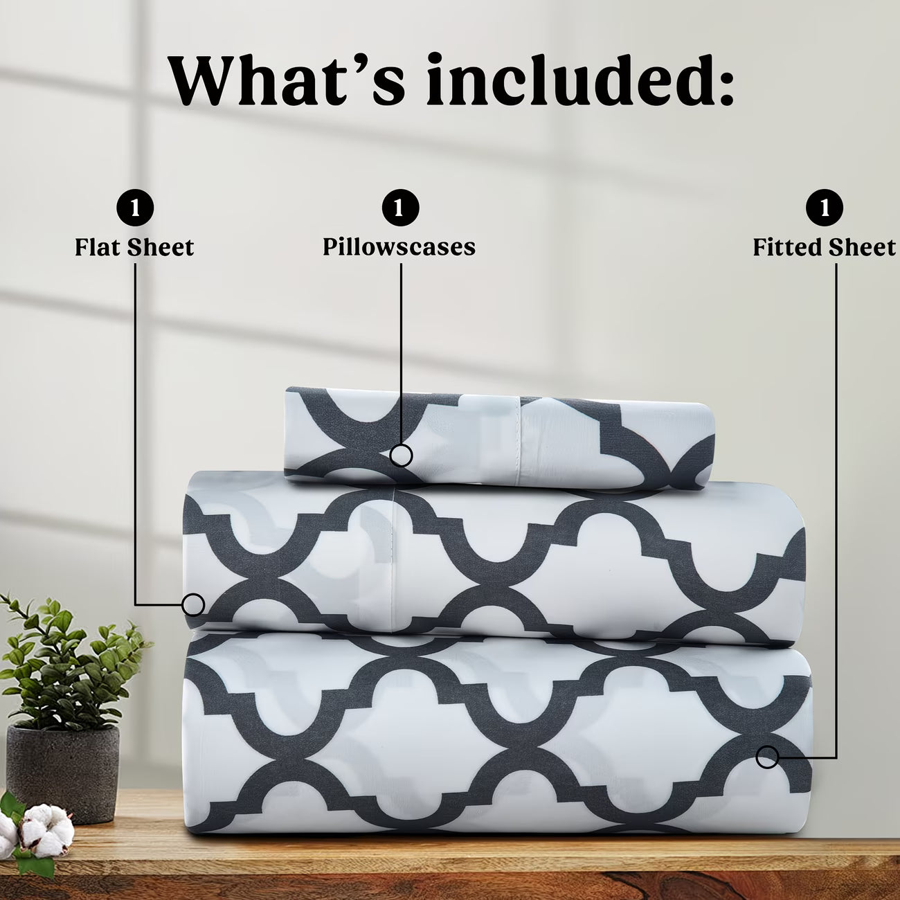 Set of patterned bed sheets with flat sheet, pillowscases, and fitted sheet on a wooden surface.