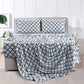 Bed with geometric patterned bedding and pillows in a bedroom setting.