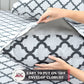 Person putting a pillow with a geometric pattern into a matching pillowcase on a bed.