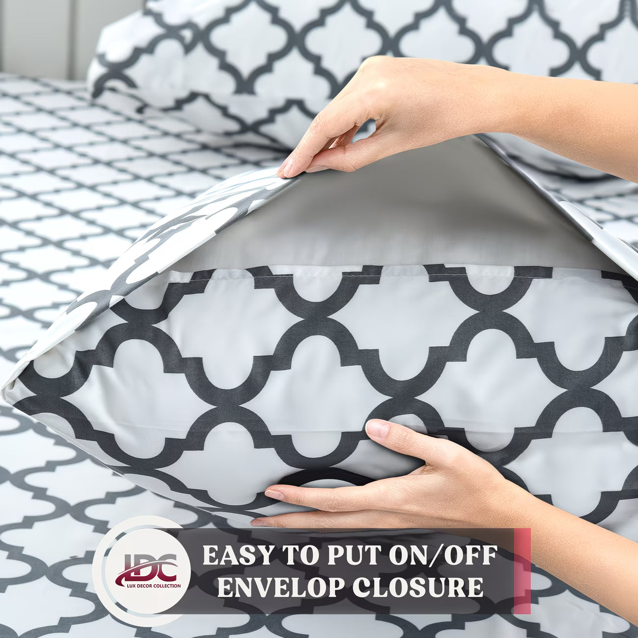 Person putting a pillow with a geometric pattern into a matching pillowcase on a bed.