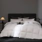 White comforter on a bed in a darkly decorated room