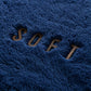 Close-up of a blue textured fabric with the word 'SOFT' embroidered on it.