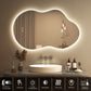Bathroom vanity with a large illuminated mirror, sink, and decorative items.