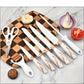 Set of knives with rose gold accents on a wooden cutting board with vegetables.