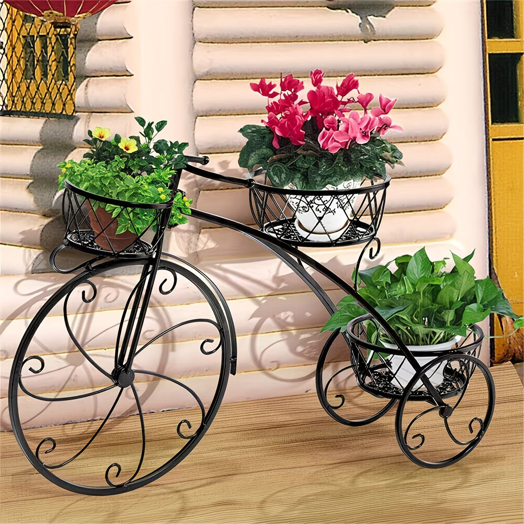 Black metal plant stand with three tiers holding potted plants against a wooden wall.