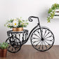 Decorative bicycle planter with flowers on a wooden floor