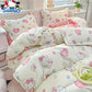 Hello Kitty themed bedding set on a bed with a window and plant in the background.