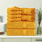 Stack of yellow towels on a bathroom counter with a vase and sink in the background.