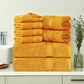 Stack of yellow towels on a bathroom counter with a sink and plant in the background.