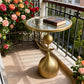 Gold side table with a book and mug on a balcony with flowers