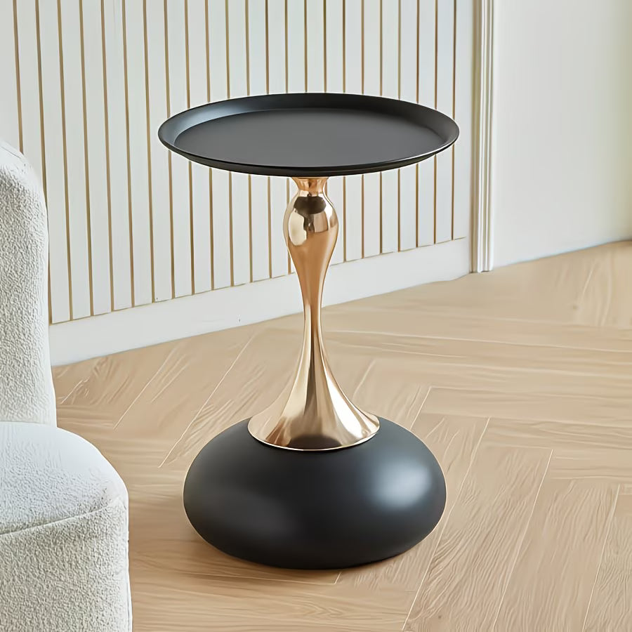 Modern side table with black and gold design on a wooden floor.